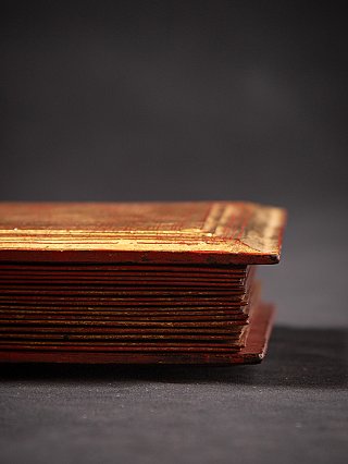 Side view of the wooden Kammavaca manuscript book showing the stacked leaves