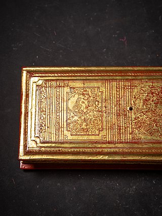 Wooden Kammavaca book cover with gilded border and red engraved design, corner detail