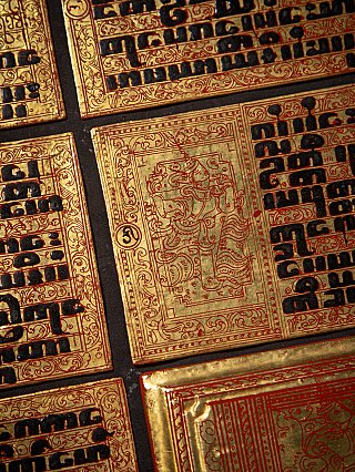 Detail of a gilded manuscript leaf with black script and a red-framed illustration panel