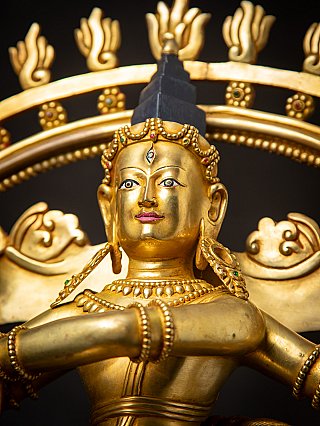 Low-angle close-up of Shiva Nataraja face with crown and halo ornaments behind