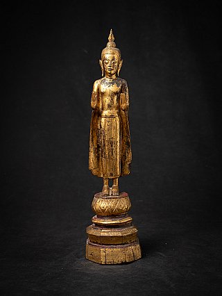 Thai wooden Buddha statue standing in abhaya mudra, full front view on tiered base