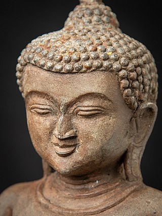 Close-up face detail of the Burmese bronze Buddha with curled hair texture and patina