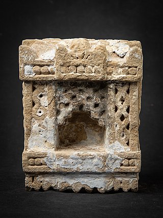 Indian stone shrine with recessed niche and weathered white residue, full front view