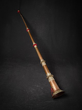 Tibetan copper dungchen horn, angled view with engraved metal bands and red rings