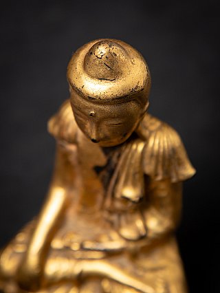 Top view detail of the head of the wooden Buddha statue, showing rounded crown and wear