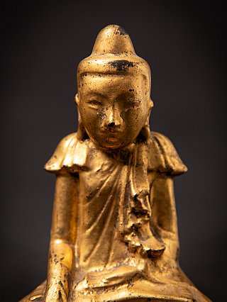 Front-facing close-up of the Buddha face with ushnisha and worn finish