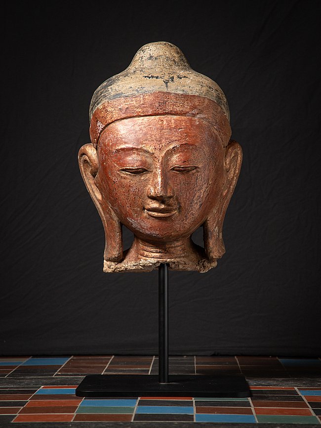 Large antique Buddha head from Burma (Myanmar) on stand, full front view with red-brown surface