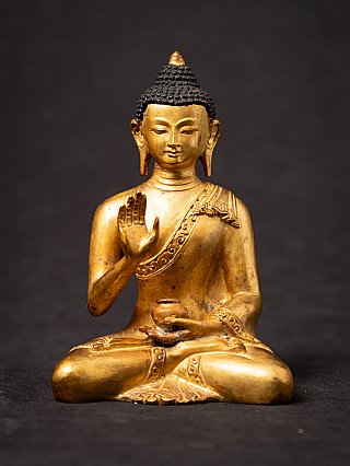Nepali bronze Buddha statue seated with raised hand in abhaya mudra, front view
