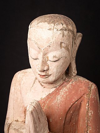 Angled top view detail of the wooden monk statue, head and praying hands
