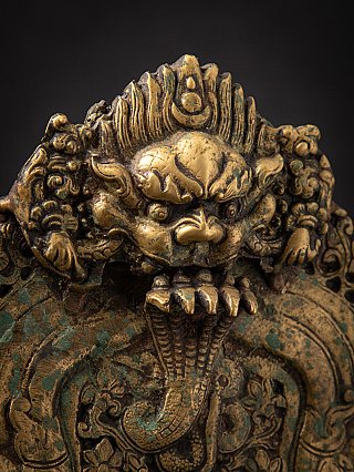 Detail of the makara head at the top of the Nepalese bronze altar, protruding tongue and patina