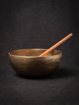 Nepali bronze singing bowl S-143 with wooden mallet resting inside, angled view