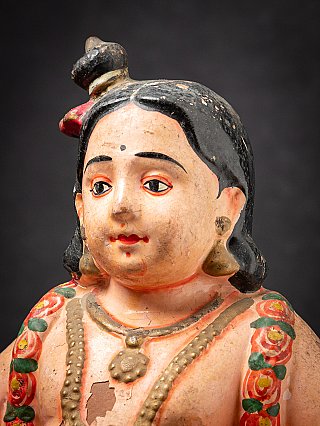 Krishna child face detail with black hair and earring, three-quarter view