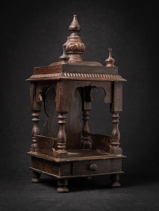 Antieke houten tempel uit India met gedraaide zuilen en knopfront, driekwartaanzicht