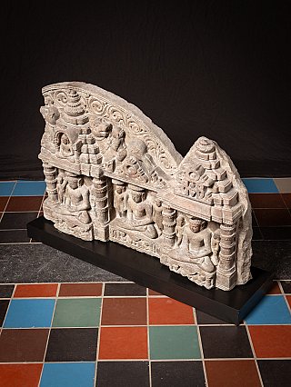 Full view of the Jain stone panel on black base, angled view showing the top edge