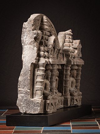Oblique left view of the Jain stone panel showing the row of pillars and seated figures