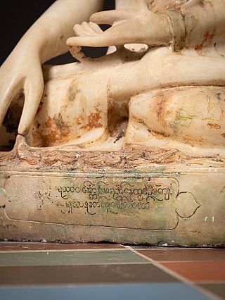 Detail der Sockelinschrift an der Marmor-Buddha-Statue mit Unterkante und Patina