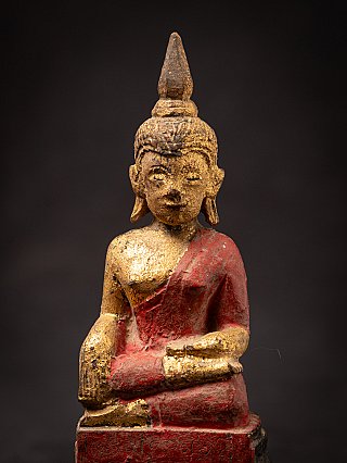 Close-up front view of the Thai Buddha statue’s head and chest with red lacquer and gilding