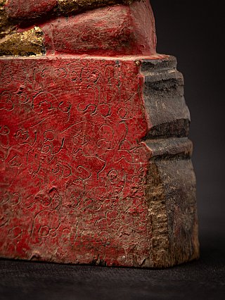 Base detail showing incised script on red lacquer and the stepped side of the pedestal