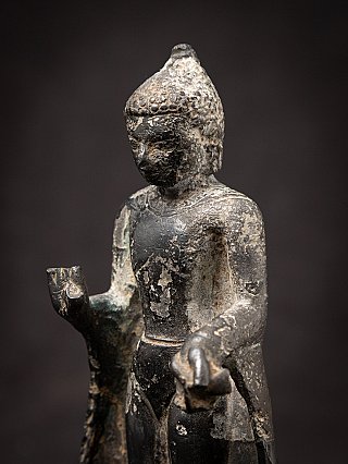 Three-quarter close-up of the bronze Buddha statue with outstretched hand and patina
