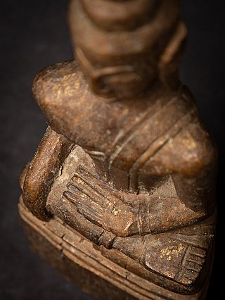 High-angle detail of the Thai wooden Buddha statue hand gesture and leg on the base