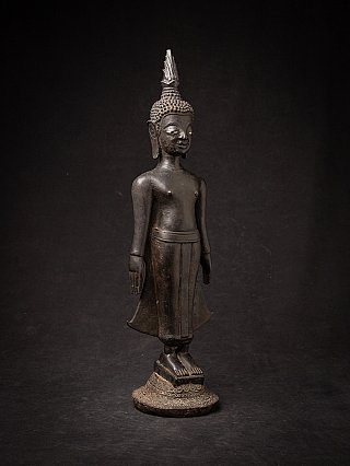 Laotian bronze Buddha statue standing in three-quarter view, feet on round base