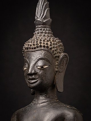 Three-quarter face detail of a Laotian bronze Buddha, showing ear and hair curls