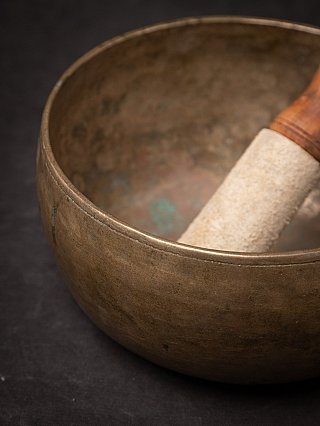 Rim detail of the Nepali bronze singing bowl with striker partially visible