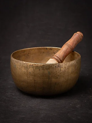 Antike nepalesische Klangschale aus Bronze mit Holzklöppel in der Schale, Dreiviertelansicht