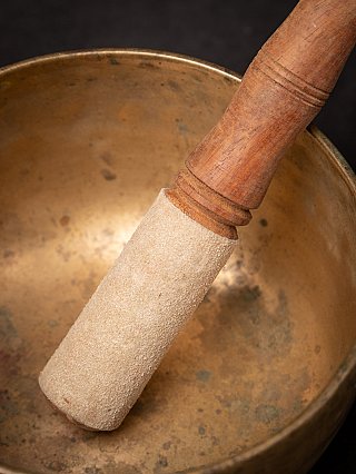 Nahaufnahme des Holzklöppels mit Bezug in der Bronzeklangschale