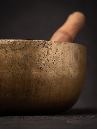 Seitendetail der nepalesischen Bronzeklangschale mit Patina, Klöppel im Hintergrund