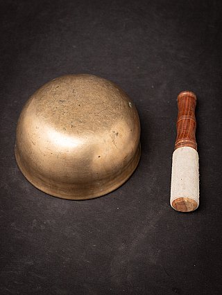 Underside view of the Nepali bronze singing bowl with striker beside it