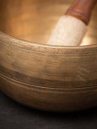 Detail van de rand en buitenwand van de bronzen zingkom uit Nepal met fijne lijnen