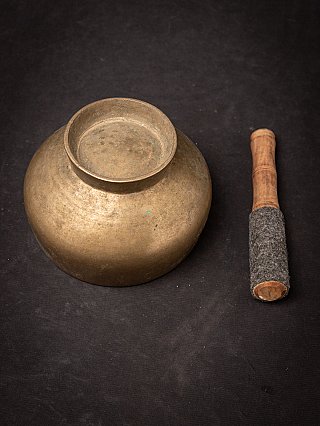 Underside of the bronze singing bowl with raised ring, striker beside it
