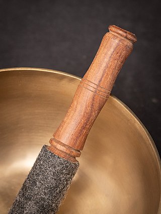 Detail of the wooden striker handle with the singing bowl in the background