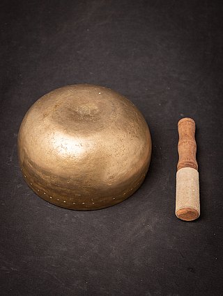 Underside of the Nepali bronze singing bowl with striker beside it