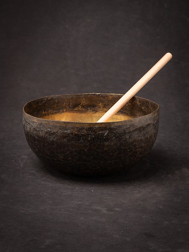 Nepalese bronzen klankschaal met houten klopper, schuin in de kom geplaatst
