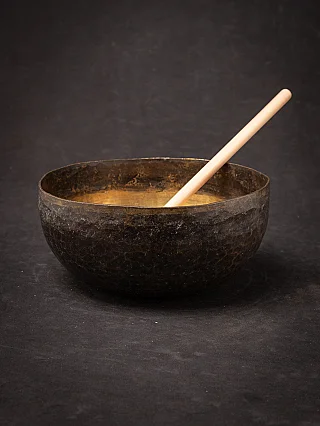 Nepali bronze singing bowl with wooden mallet resting diagonally inside