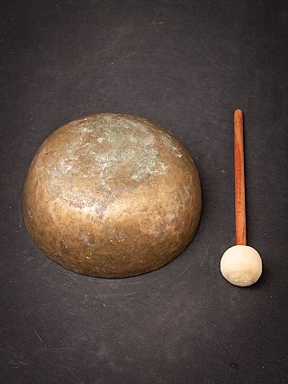Underside view of the Nepali bronze singing bowl with mallet beside it