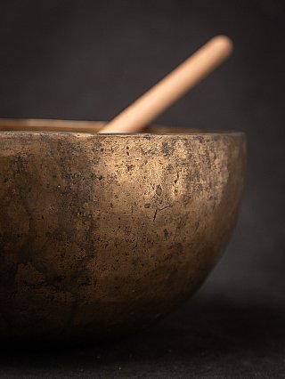 Side detail of the Nepali bronze singing bowl with blurred mallet in background