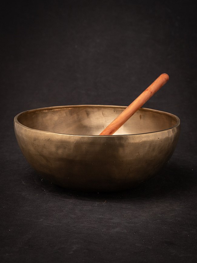 Nepali bronze singing bowl with wooden mallet resting diagonally inside