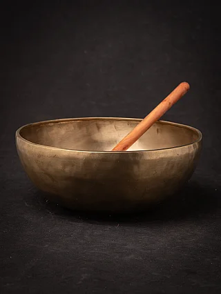 Nepali bronze singing bowl with wooden mallet resting diagonally inside