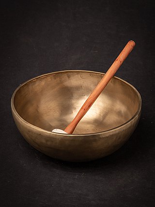 Nepali bronze singing bowl with wooden mallet standing inside the bowl