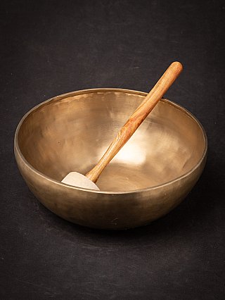 Nepali bronze singing bowl with mallet leaning inside, rim visible