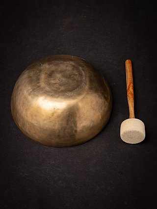 Underside of the Nepali bronze singing bowl with mallet beside it
