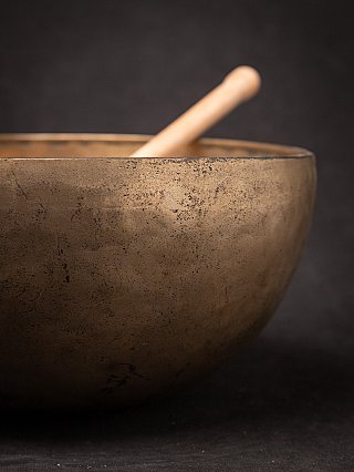 Close-up of the rim and side of a Nepali bronze singing bowl with blurred mallet inside