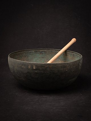Bronzen Nepalese klankschaal met houten klopper in de schaal, schuin aanzicht