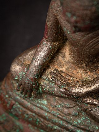 Hands detail of the bronze Buddha showing bhumisparsha mudra and green patina