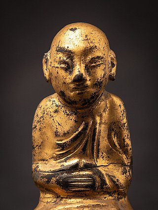 Face and hands detail of the wooden Burmese monk statue, frontal view