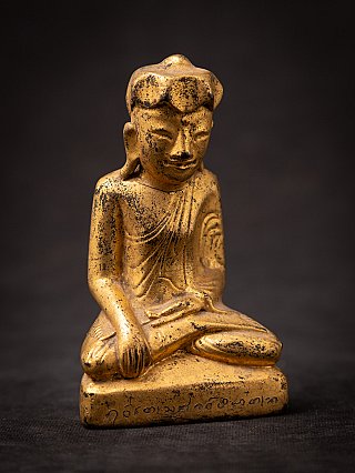 Burmese wooden Buddha statue, three-quarter view with inscription visible along the front edge of the base