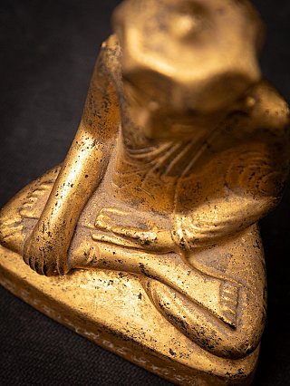 Angled top view showing the seated posture and hands, including the lowered hand by the knee
